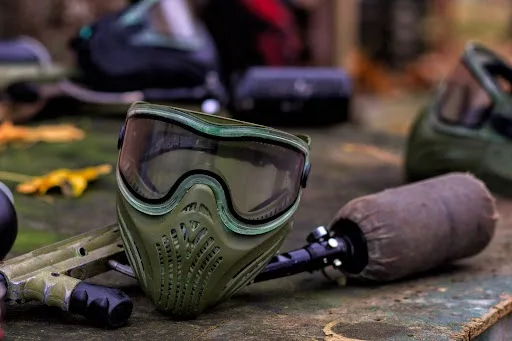 Paintball Marker and Safety Mask laying on a wooden background at Cousins Paintball.